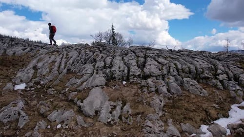 Hiking on Rocky Terrain With Cloud Formations in Mountainous Landscape