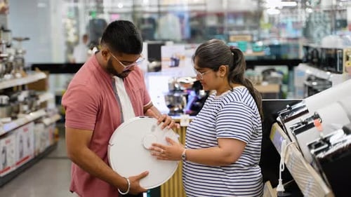 Indian Asian Couple Choosing Robot Vacuum Cleaner in Electronics Store