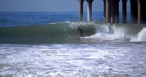 Surfer rides a huge wave in slow motion at a tropical beach in Hawaii or Florida