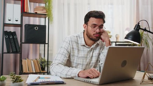 Bored Sleepy Businessman Worker Working on Laptop Computer Yawning Leaning on Hand at Home Office