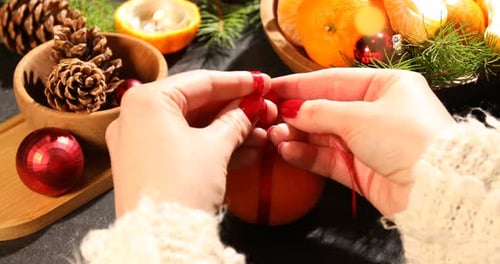 Femme nouant un nœud sur une mandarine à une table noire, gros plan