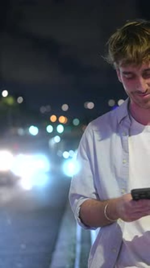 Handsome Young Man Using Smartphone at Night in the City