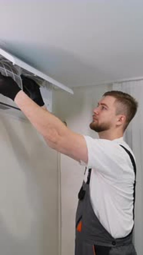 Maintenance Man Changing Air Conditioning Filter in Home