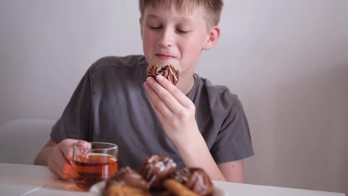 Boy Enjoying Cookies and Tea at Table