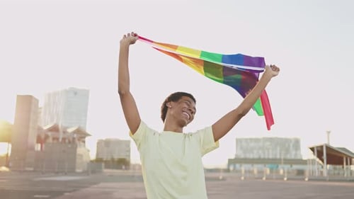 Young Adult Raising Rainbow Flag Outdoors