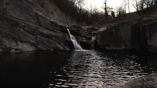 Drone still flight over some stones and a waterfall at daytime near a stone
