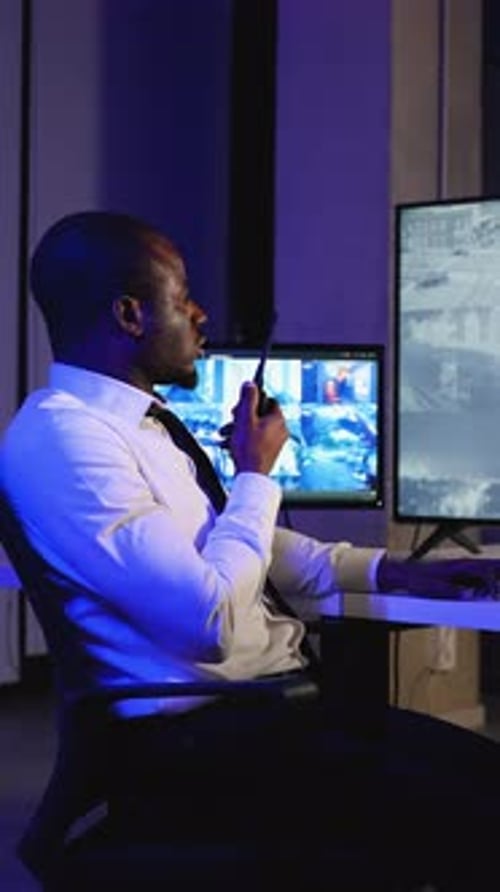 Security Guard Communicating with Walkie Talkie in Office