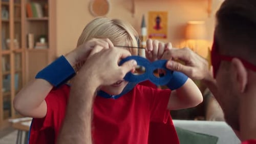 Father Helps Young Boy with Superhero Mask