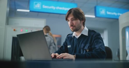 Airport Security Checkpoint Portrait of TSA Worker Using Laptop Looking at Camera