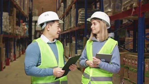 Warehouse Workers Discussing Inventory Using Tablet and Clipboard
