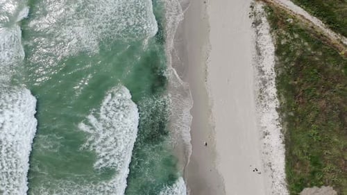 Aerial Drone View Of Foamy Waves Onto White Sandy Shoreline.