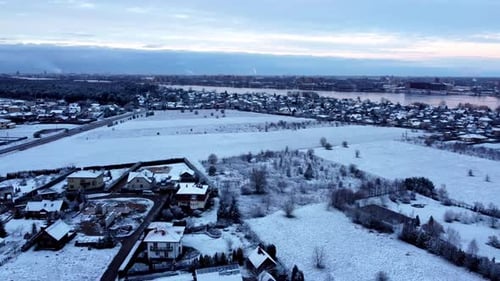 Aerial Winter Sunset Over a Frozen River and Snowy Village