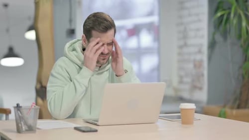 Man Working at Desk Massaging Temples