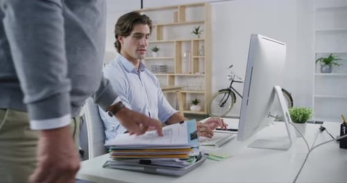 4k video footage of a man handing a young businessman a pile of paperwork in a modern office