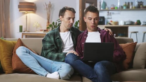 Young Adults Using Laptop on Couch Together