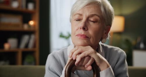Senior Woman Contemplating Resting Hands on Cane