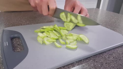 Chopping board with cucumber being chopped.