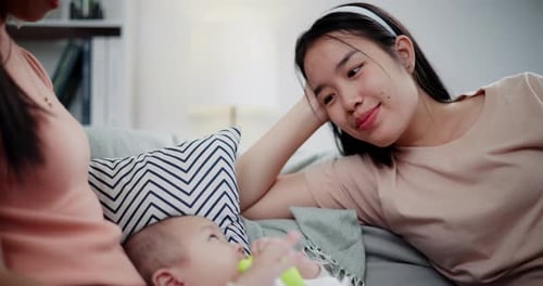 Infant Plays with Toy Near Women on Couch