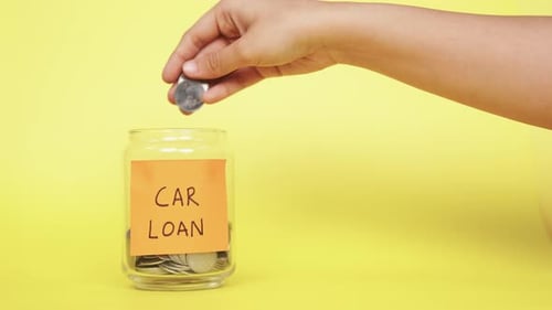 Saving money to pay Car Loan. Putting Indian Rupee coins into the glass jar