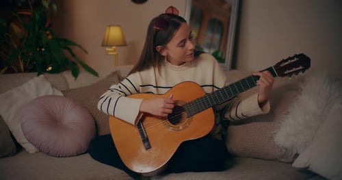 Young Woman Plays Guitar at Home