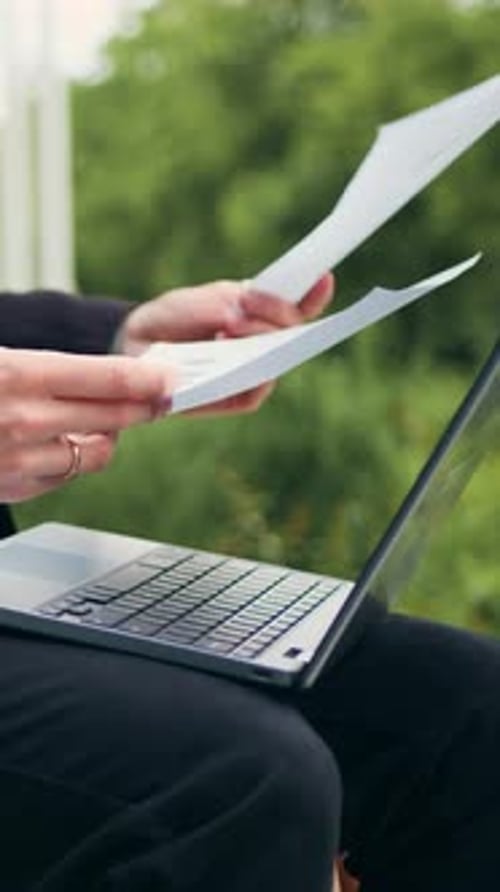 Close Up Hands Businessman Reading Documents with Financial Data and Using Laptop Sitting on Bench