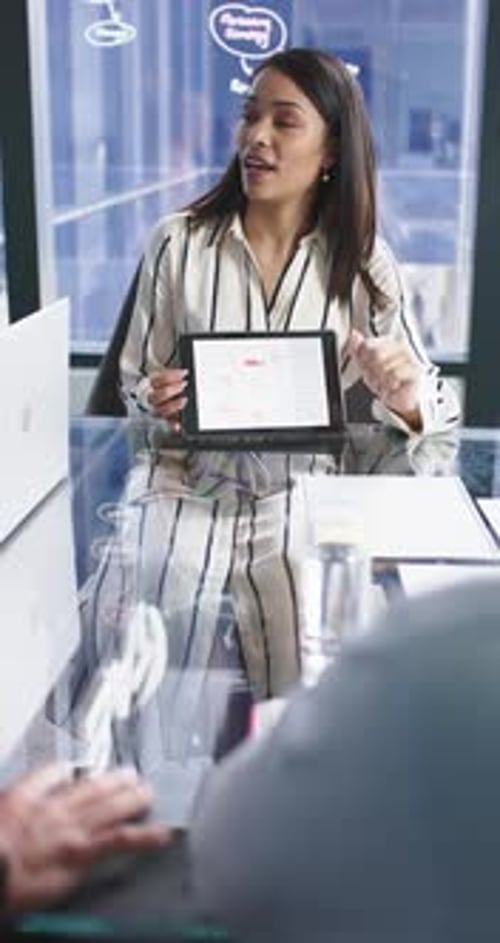 Vertical video: Presenting data on tablet, businesswoman leading meeting in modern office