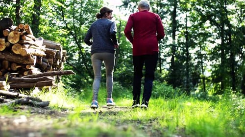 Rear View of Senior Sporty Couple Running in the Forest Outdoors In