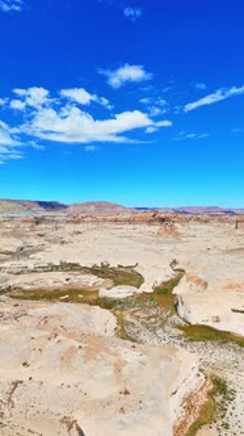 Deserted rocky landscape with spectacular canyons. Small fluffy clouds in the blue sky above.