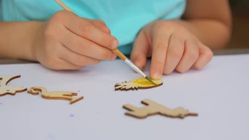 Child Paints Wooden Pineapple Craft with Brush