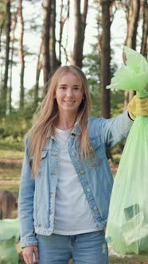 Woman Holding Trash Bag in Sunny Woods