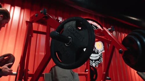 Man Adds Weights to Barbell at the Gym