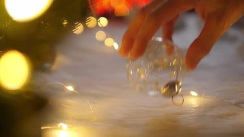 Hand Placing Christmas Ornament on Cozy Surface