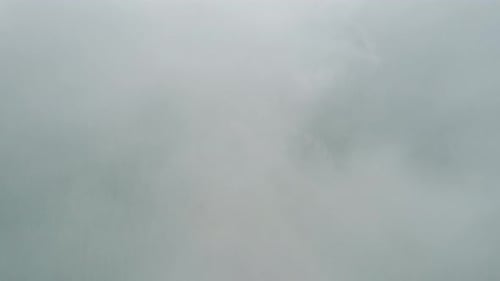 Fantastic Aerial Flight Through Clouds in the Mountains with Forest Below