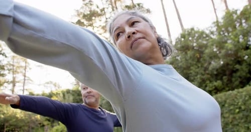 Focused diverse senior couple practicing yoga in garden