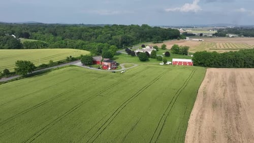 Autos an der Kreuzung eines rot gefärbten Bauernhauses in Amerika. Sonniger Tag in der Sommersaison. Dolly