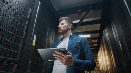 Young Skilled IT Engineer Servicing Rack Server Cabinets in Data Center