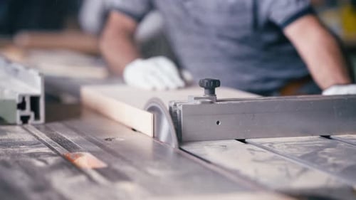 Carpenter Using Table Saw for Cutting Wood Plank