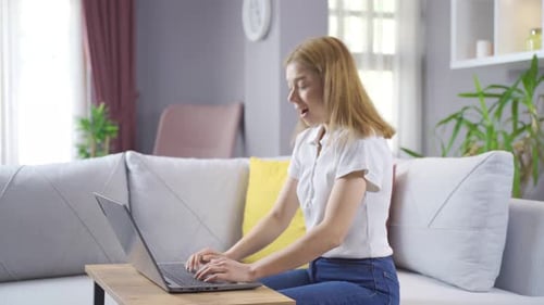 Woman Celebrates Success While Working on Laptop at Home