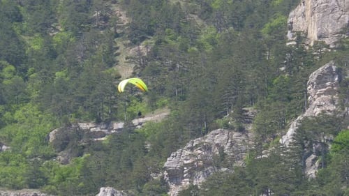 Paramotorfliegender Fallschirmspringer mit Motor fliegt vor der Kulisse der Berge