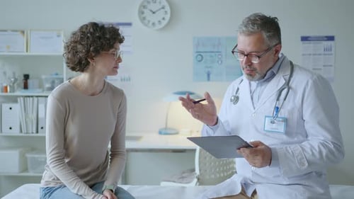 Doctor and Female Patient Sitting on Examination Table Having Talk in Clinic