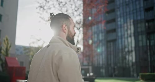 Young Man with Stylish Trendy Hairstyle and Beard in Casual Clothes Walking Down the Street in Urban
