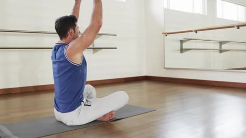 Focused caucasian man practicing yoga meditation in gym, slow motion