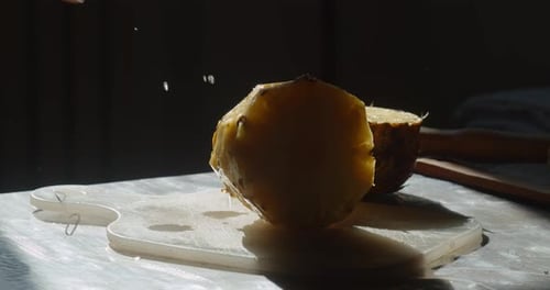 Hand putting pineapple on a chopping board, close up, slow motion