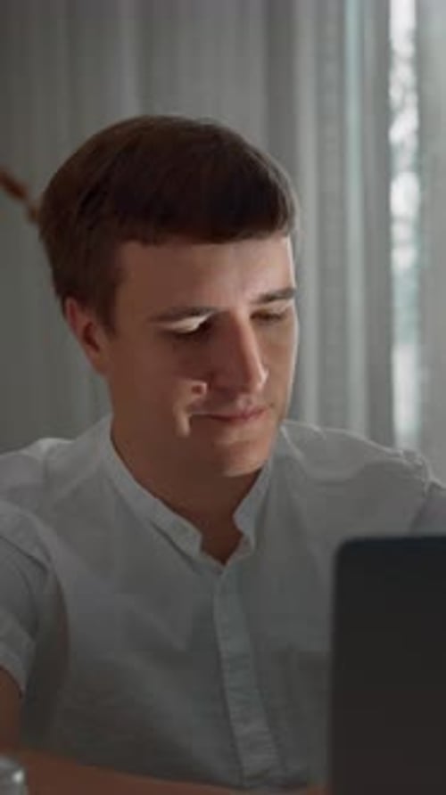 Young Man Works on Laptop Indoors, Portrait