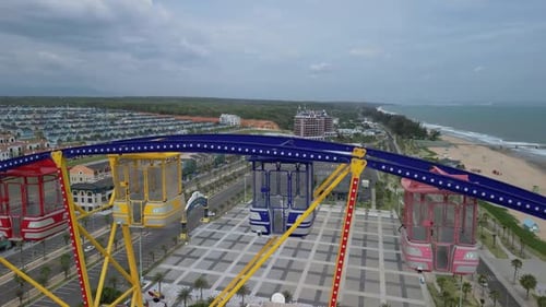 Aerial View of Around a Nonspinning Ferris Wheel in an Amusement Park with the Sea and Beach in the