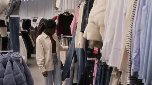 Woman Looking through Clothing Items in Sales Section of Clothes Store