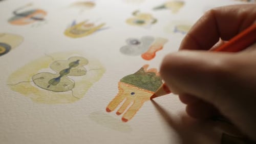 Hand holding color pencil and drawing colorful abstract shapes, close up