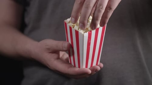 Hand Reaching into Delicious Popcorn Container