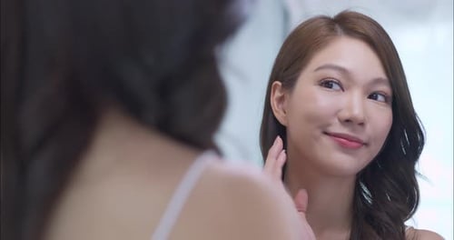 Woman Looking in Mirror Touches Her Face