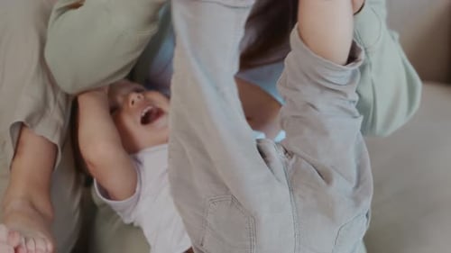 Happy Woman Plays with Laughing Baby at Home